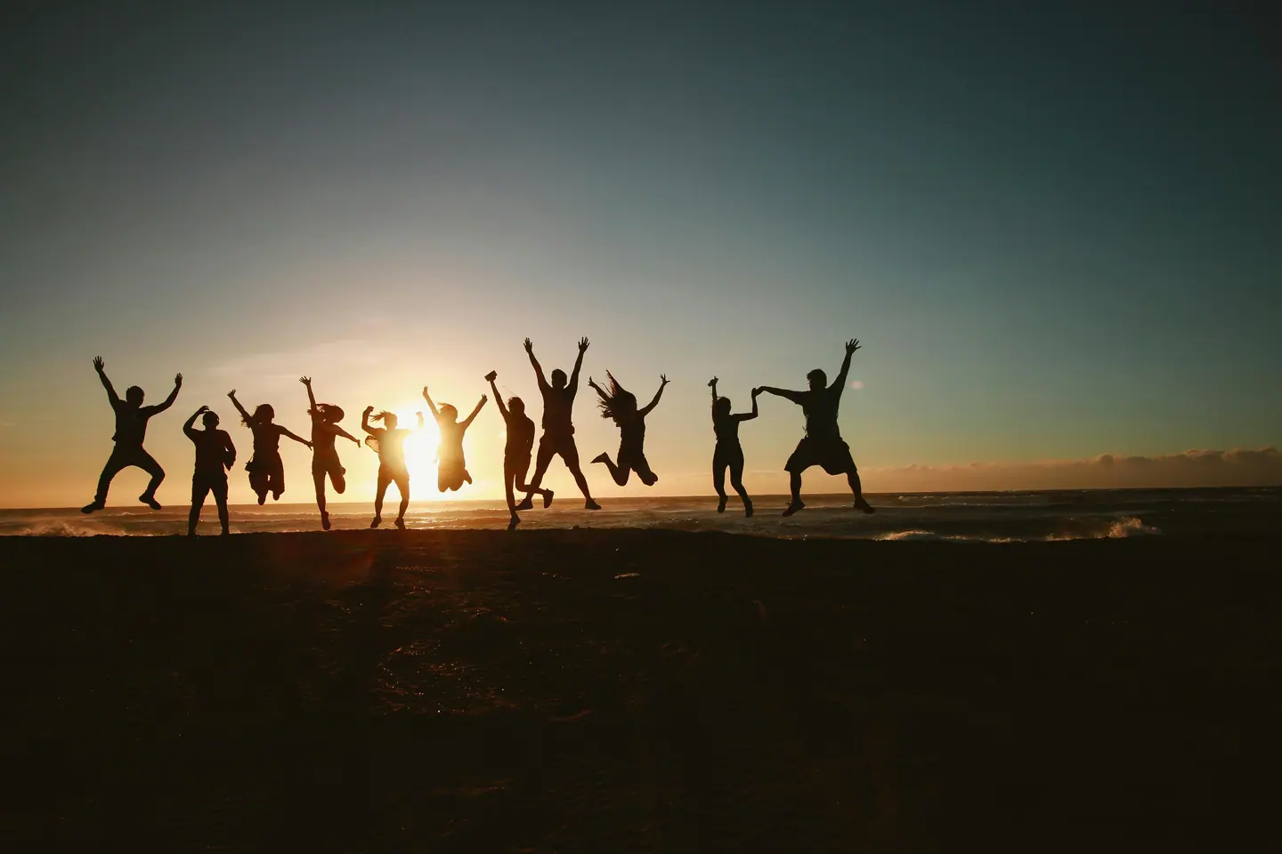 Group of friends jumping on a beach at sunset